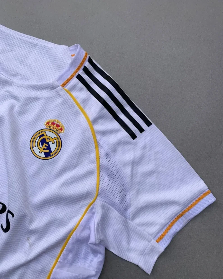 The Dribble Store Real Madrid 2025 home jersey white mesh with club crest black shoulder stripes and gold trim