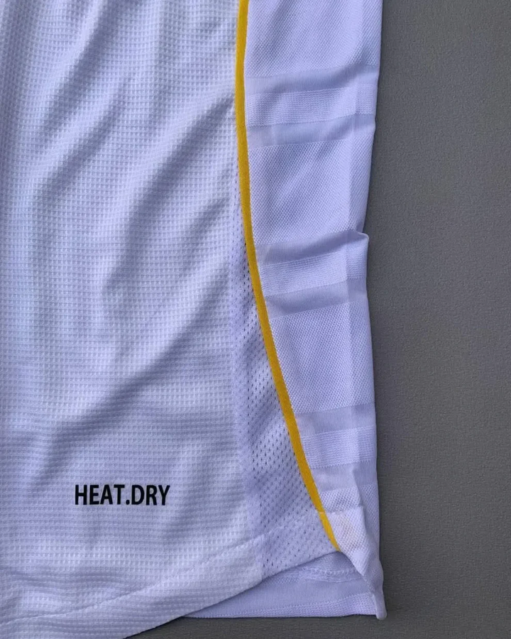 The Dribble Store close up of Real Madrid 2025 home jersey white mesh with yellow side piping and HEAT DRY branding