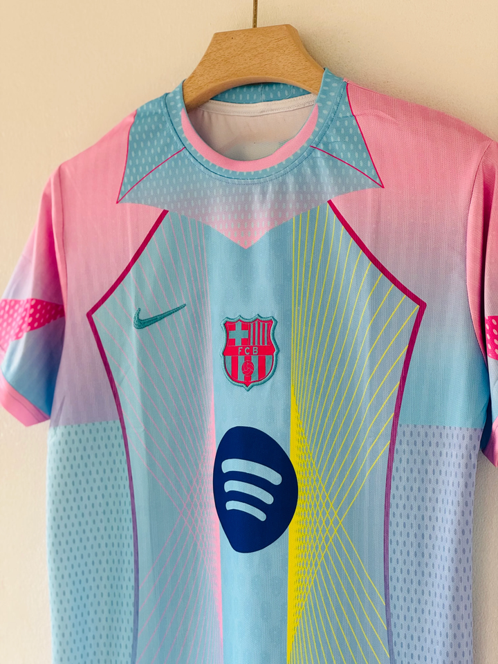 FC Barcelona Blue Edition Jersey 2025-26 hanging on wooden hanger pastel pink and blue gradient with crest and Nike logo