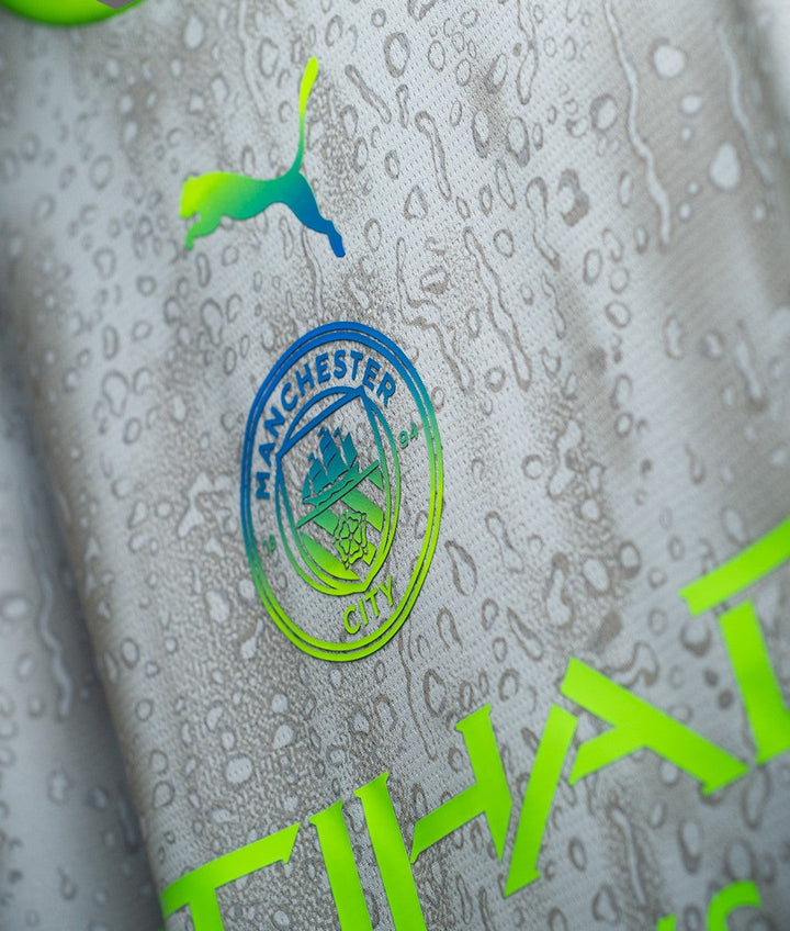 The Dribble Store close up of Manchester City Third Jersey 2025-26 grey fabric with crest Puma logo and water droplets